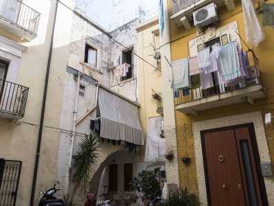Qui tra tende da sole e biancheria messa ad asciugare notiamo un fregio con mascherone sulla finestra di un palazzo ocra, mentre solo uno "slalom" tra le piante permette di passar sotto l'arco rampante posto all'ingresso di una delle casette